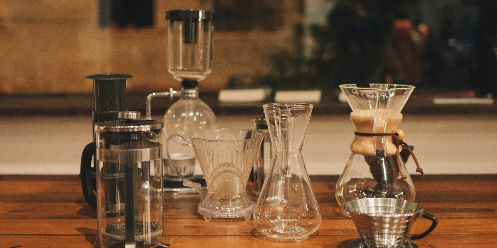 A selection of manual coffee brewers on a wooden counter