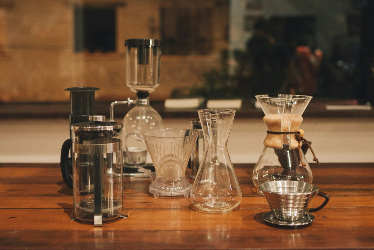 A selection of manual coffee brewers on a wooden counter