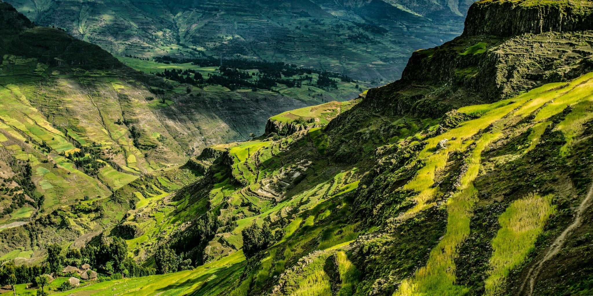 Green mountain slopes and a steep valley with cultivated fields