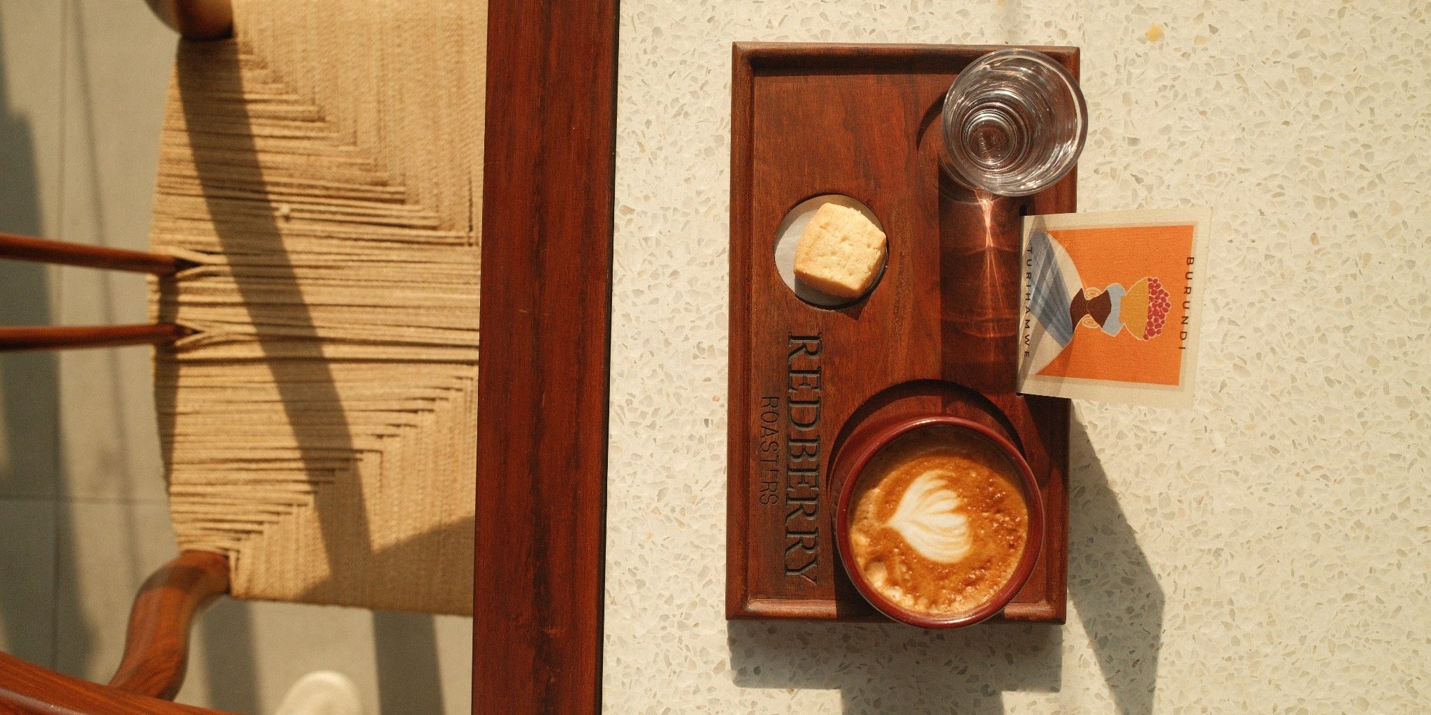 Coffee served with a biscuit, water and a Burundi information card on a Red Berry Roasters tray