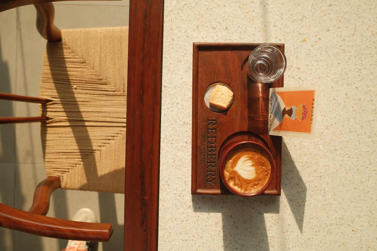 Coffee served with a biscuit, water and a Burundi information card on a Red Berry Roasters tray