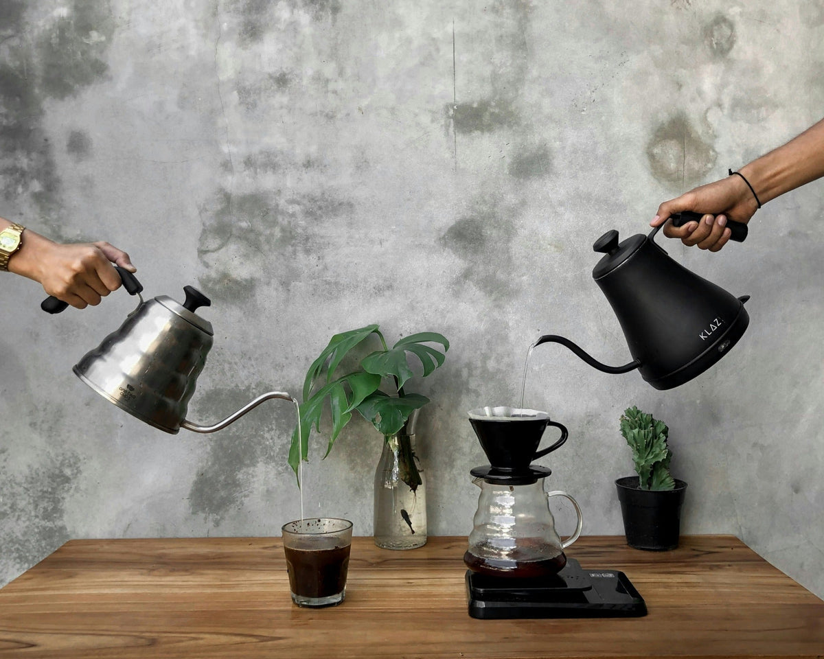 Pour-over coffee setup with gooseneck kettles and a dripper over a glass server